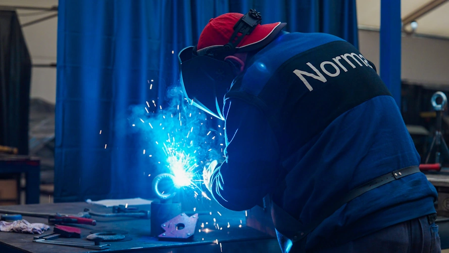 Spawacz łączy elementy konstrukcji w certyfikowanej spawalni Norma