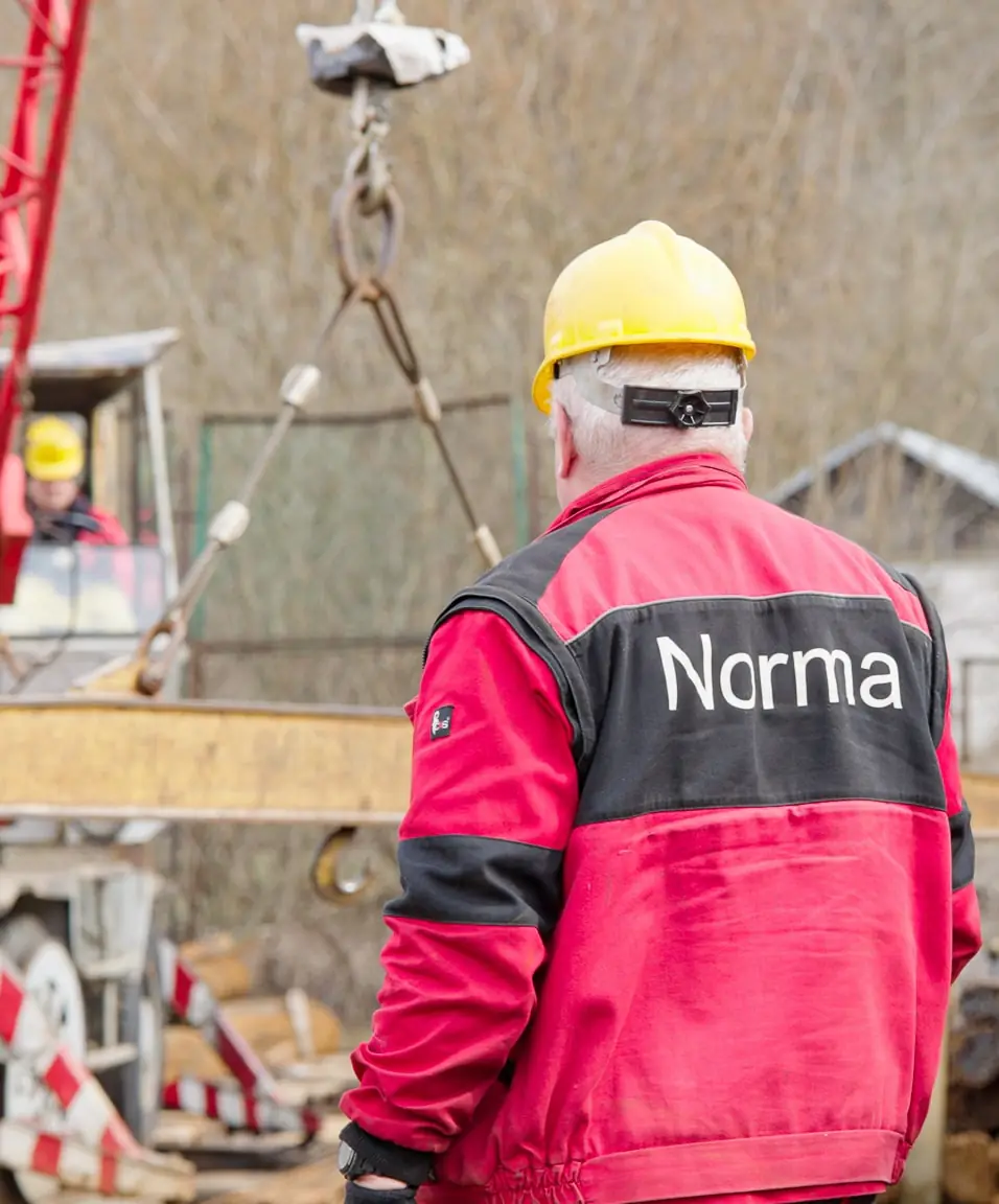 Pracownik Norma nadzoruje podnoszenie elementów stalowych żurawiem